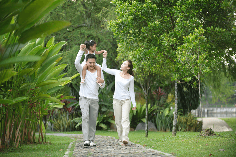 Parents walking down foliage path with daugher on dad's shoulders